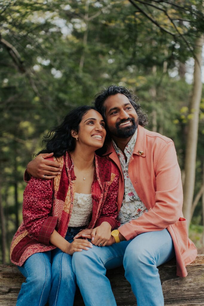 Couple smiling and looking off into the distance hugging in the forest. Hamilton Wedding Photographer