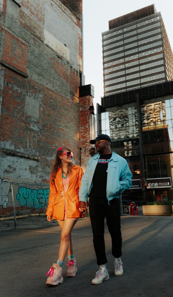 Couple smiling looking at each other and holding hands downtown in retro outfits. Hamilton Wedding Photographer